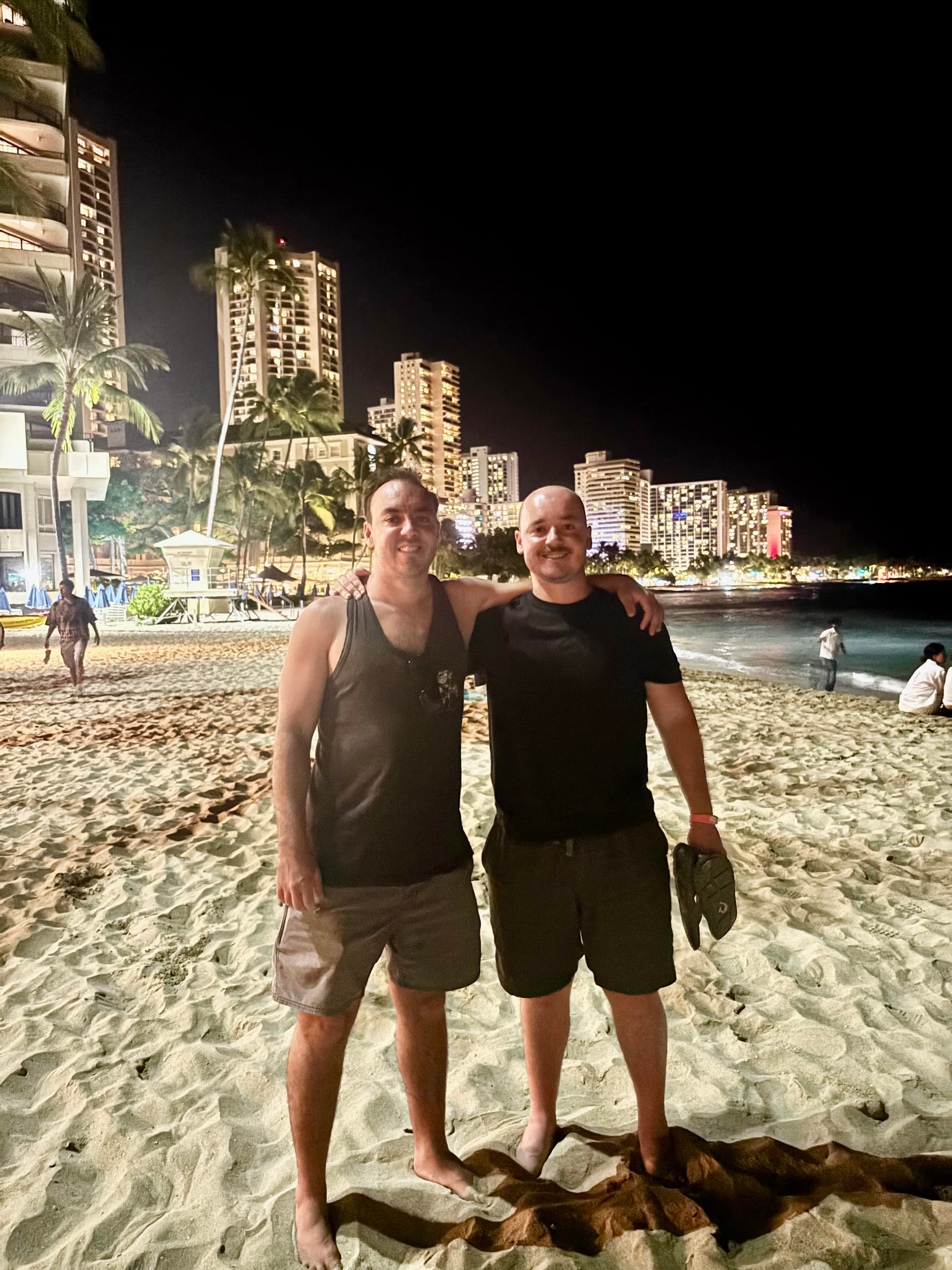 Dane Kreisman and Dylan Kreisman standing together on a beach at night.